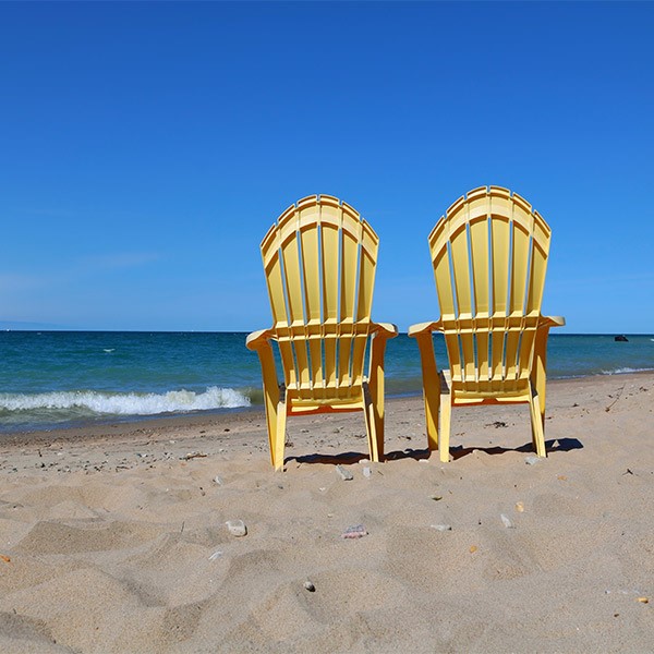صندلی پلاستیکی ساحلی و دسته دار مقابل دریا و زرد رنگ